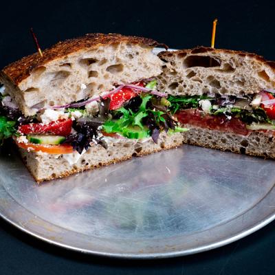 Veggie focaccia sandwich cut in half served on a metal tray.