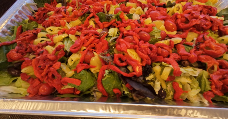 Mixed salad with greens, peppers, and cherry tomatoes in a tray