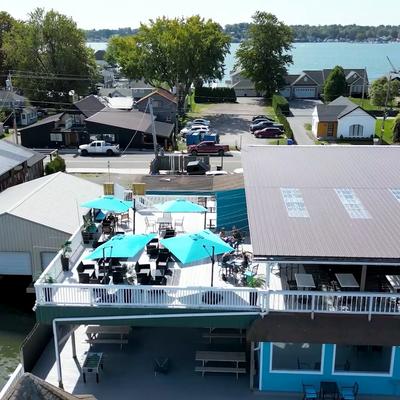 Aerial view of a rooftop dining area with lake views and bright blue umbrellas.