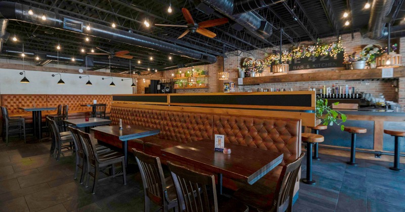 Interior of a modern restaurant with wooden tables and tufted leather booths