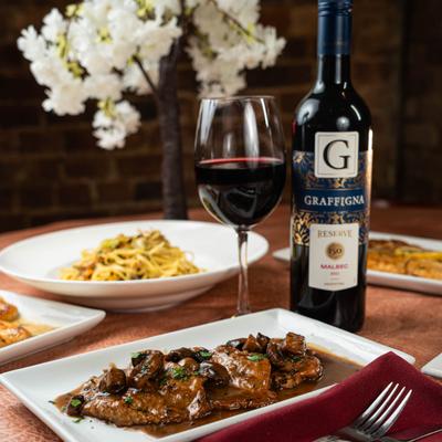 Scaloppine marsala served with mushrooms and sauce, accompanied by red wine.
