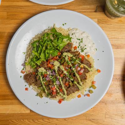 Beef Shawarma Bowl served with rice, fresh vegetables and sauces.