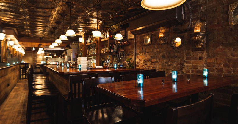 Interior, high seating, old brick wall on the right, bar in the back, small lanterns on the table