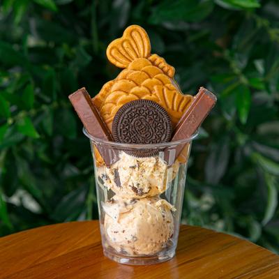 A dessert cup with ice cream, chocolate bars, and cookies.