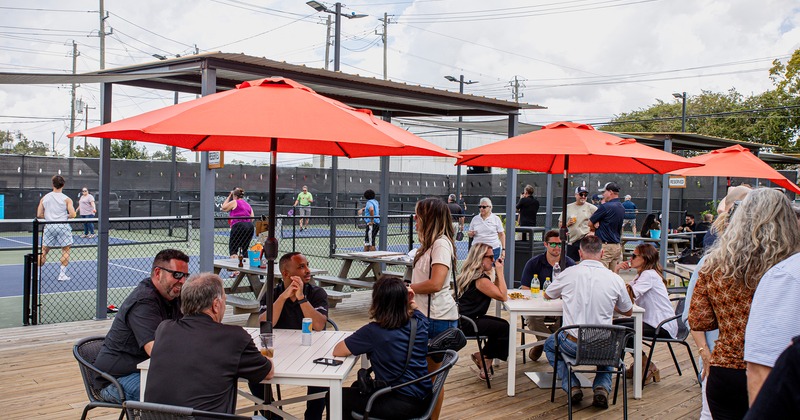 Outdoor seating area next to the tennis courts, guests sitting at tables