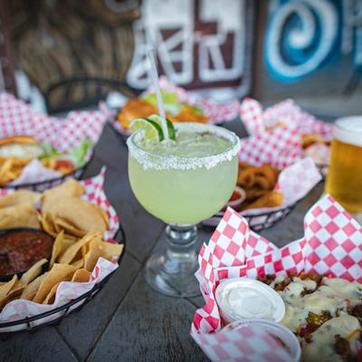 Margarita drink surrounded by assorted dishes.