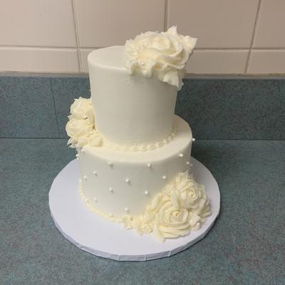 A two tiered white wedding cake with white floral decorations wedding cakes