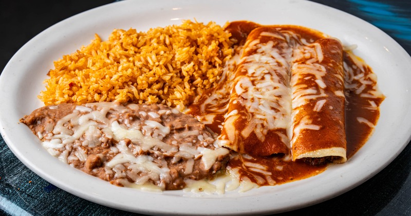 Two red enchiladas, rice, and beans
