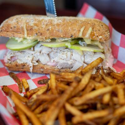 Turkey sandwich with melted brie cheese, green apples, cranberry mayo, and fries.