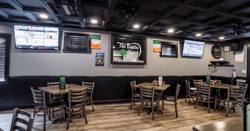 Interior, wooden tables, leather chairs, two televisions displaying sports, flags on the wall