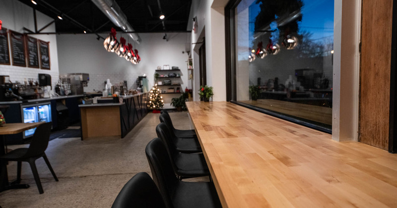 Interior, high seating by the window, wooden table, bar stools, bar in the back