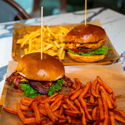 Bacon cheese burger with sweet potato fries, and a chicken sandwich with French fries.