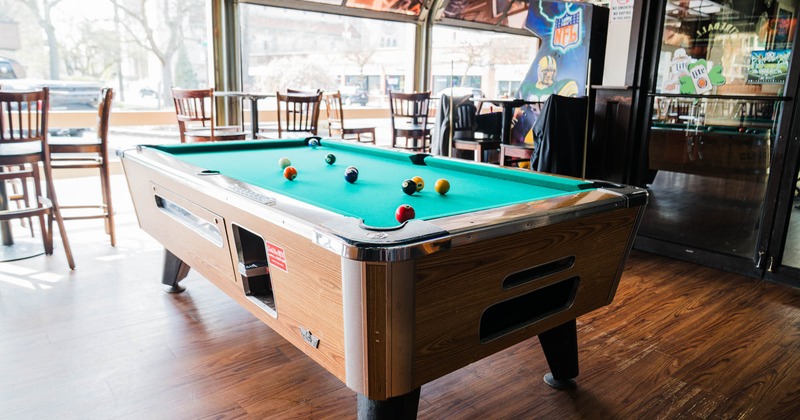 Interior, billiards table, tables with chairs in the back, large shop windows