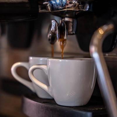Fresh coffee dripping into two coffee mugs from a coffee machine.