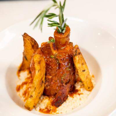 Pork Osso Bucco served with risotto, potatoes and fresh rosemary.