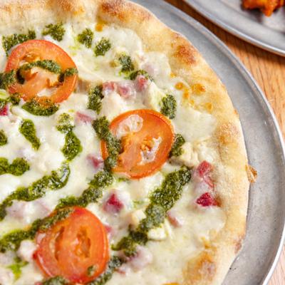 White chicken pizza with pesto drizzle.
