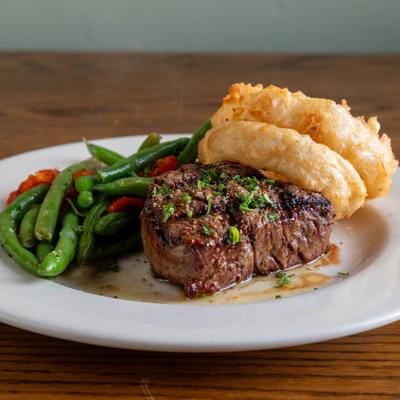 Grilled filet mignon paired with crispy onion rings and green beans.
