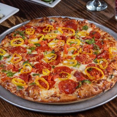 Pizza topped with cheese, pepperoni, banana peppers and green onion.