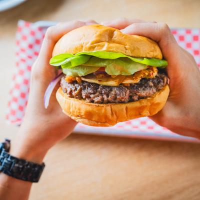 Hands holding a burger with lettuce.
