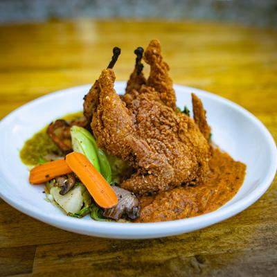 Whole fried quail, served with a rich sauce and roasted vegetables.