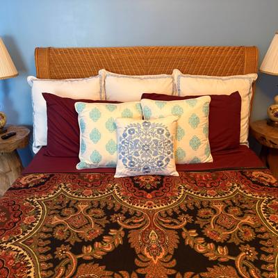 Bed with an ornate quilt and accent cushions.