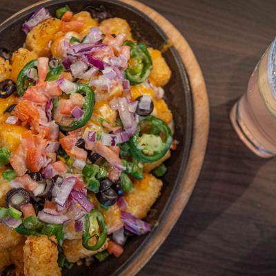 Tater tot nachos with jalapenos, red onion, tomatoes, black olives, peppers, cheese