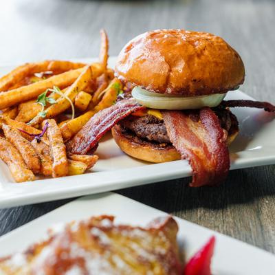 Bacon cheeseburger accompanied by seasoned fries.