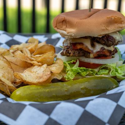 WT smash burger with chips and a pickle on the side.
