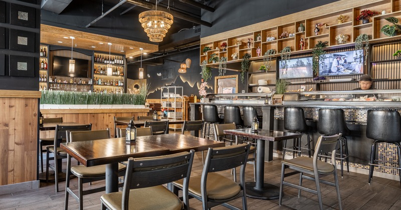 Diner area, tables, chairs, bar behind, tv screens on wall behind food counter