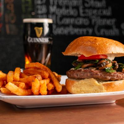 Burger with fries and a glass of dark beer in the background.