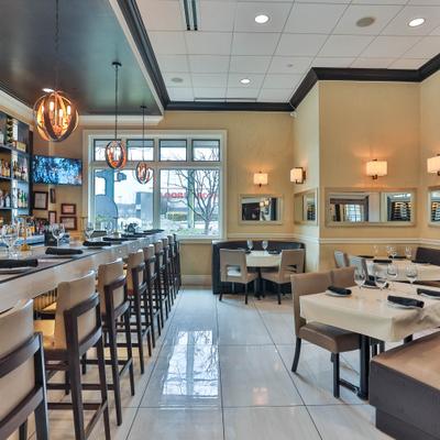 Bright restaurant interior with bar seating and set tables.