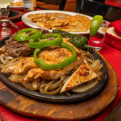 Steak and chicken fajitas topped with green pepper slices and a grilled jalapeno.