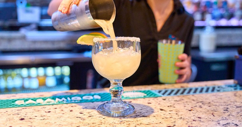 A bartender pouring a cocktail drink from a shaker