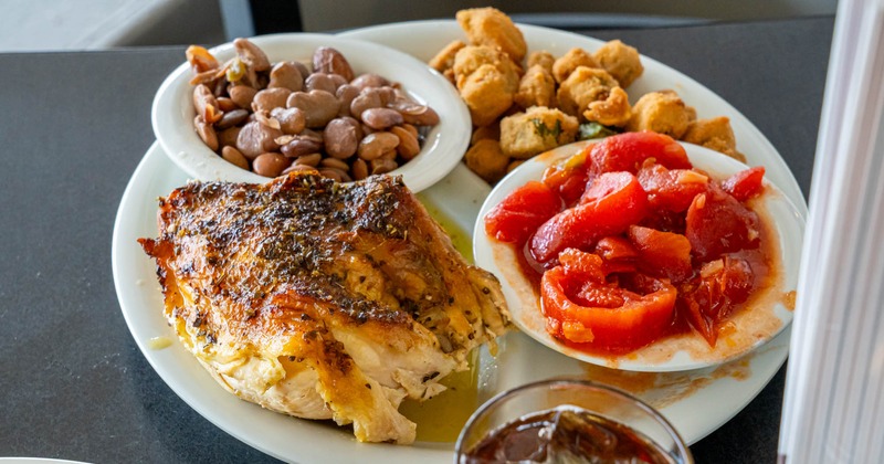 Roasted chicken with stewed tomatoes, pinto beans, fried okra, and a glass of iced tea