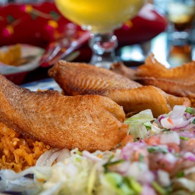 Fried tilapia served on a bed of rice with a salad on the side, close-up.
