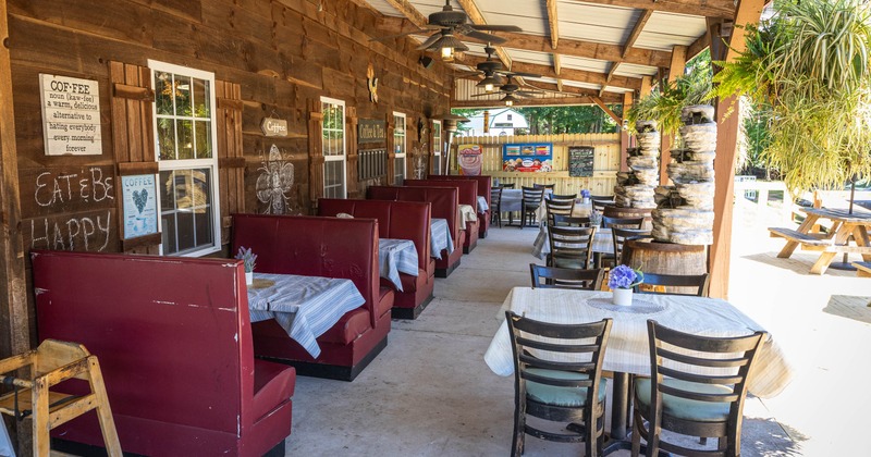 Outdoor dining area, red booths, tables with floral arrangements