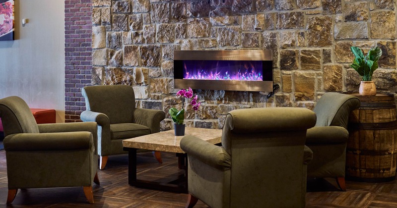 Interior, lounge area, four comfy armchairs with coffee table, stone wall, screen fireplace