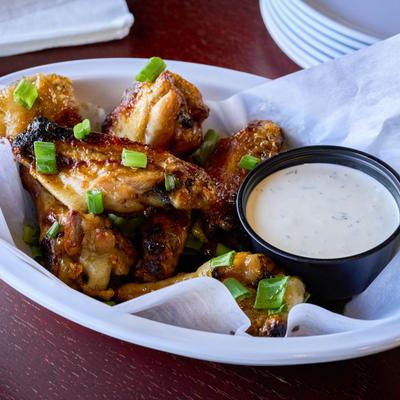 Spicy Asian zing wings with scallions and dipping sauce.