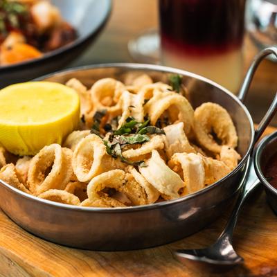 Fried Calamari garnished with herbs and served with a half of lemon.