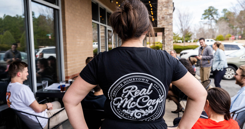 Outside, staff member wearing a T-shirt with the restaurant's logo printed on the back