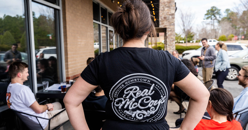 Outside, staff member wearing a T-shirt with the restaurant's logo printed on the back