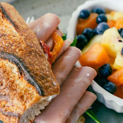 A close up of Ham Baguette with fresh fruit on the side.