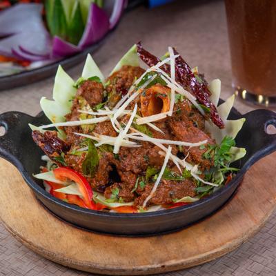 Spicy mutton sukka served hot in a cast iron skillet skillet.