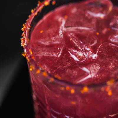 Pomegrade Margarita served in chili-rimmed glass, close-up.