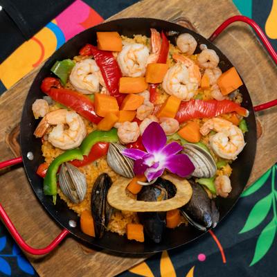 Seafood paella with shrimp, mussels, vegetables, and flower garnish.