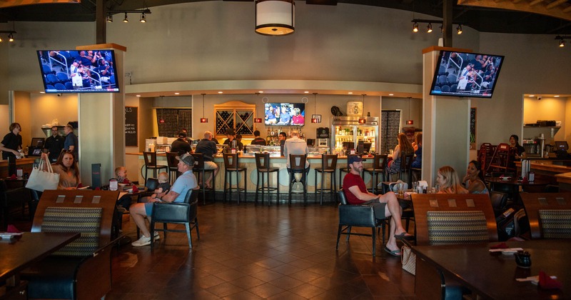 Diner area, tables and chairs, guests, bar area behind