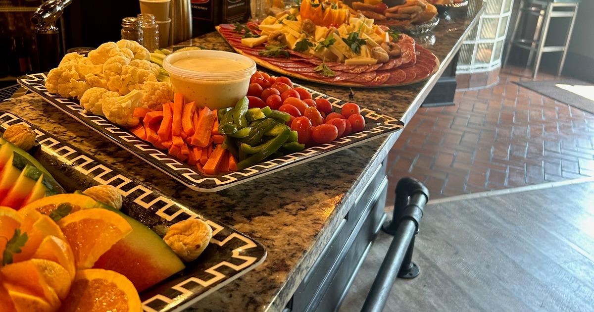 Buffet table with a vegetable platter, fruit platter, and a charcuterie board