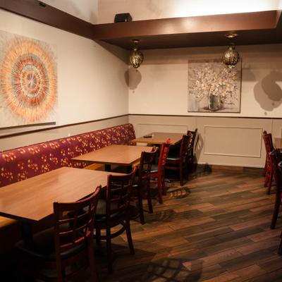 Dining area featuring wooden tables, chairs, banquette, and abstract wall art.