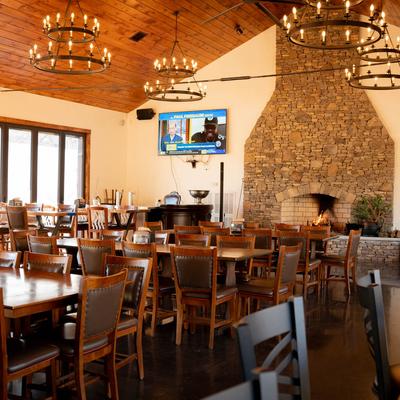 Seating area featuring tables, chairs, stone fireplace, and wheel chandeliers.