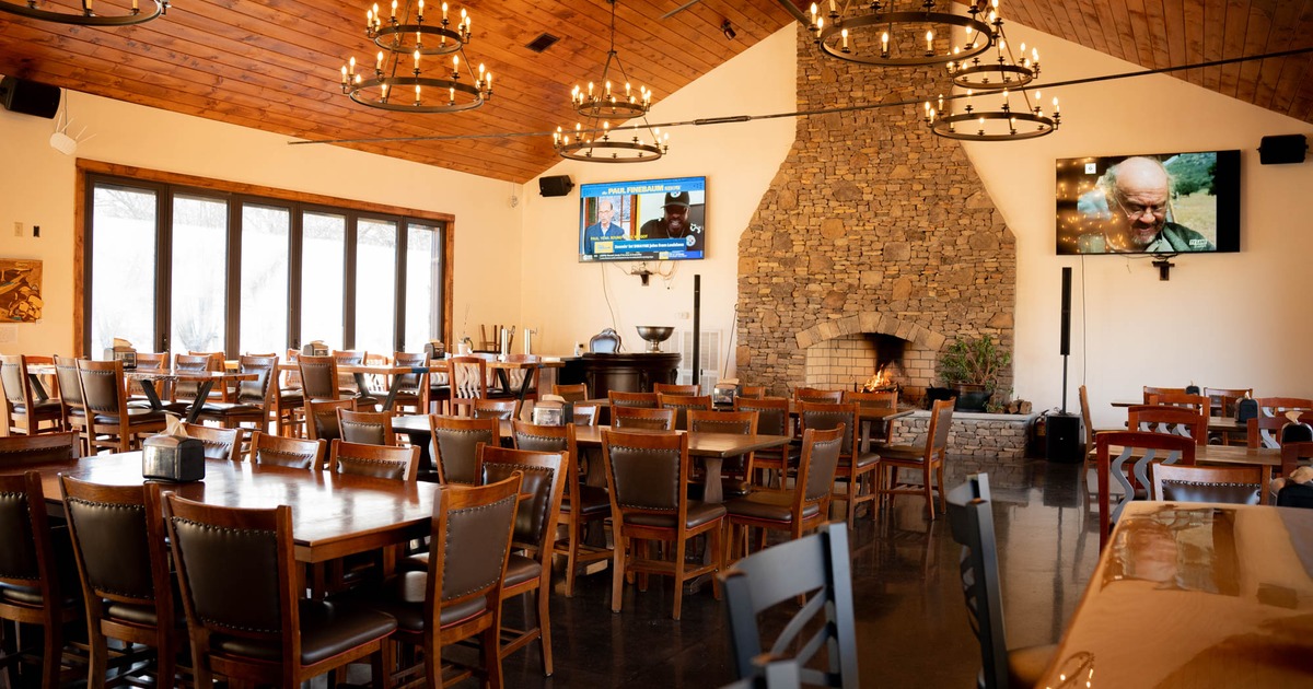 Seating area featuring tables, chairs, stone fireplace, and wheel chandeliers
